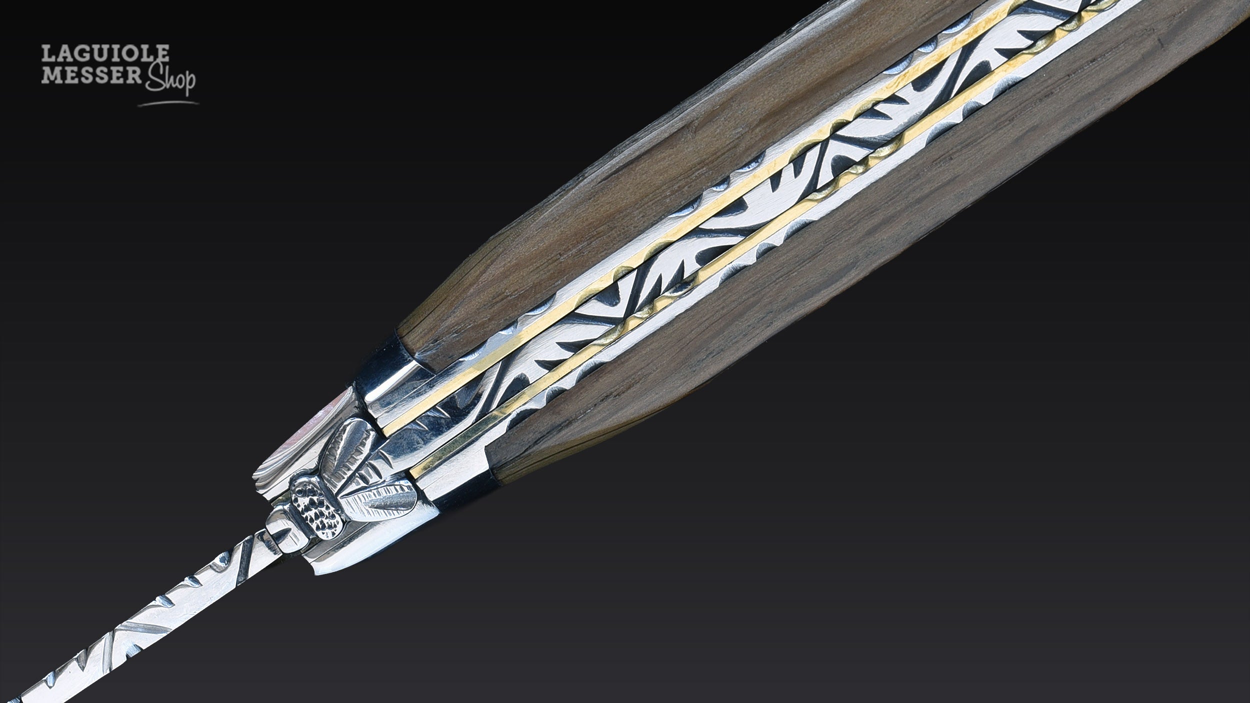 Detailansicht des Forge de Laguiole Taschenmessers mit Mooreichenrinde-Griff, ziselierter Biene, Messinglinie und kunstvoll guillochiertem Messerrücken