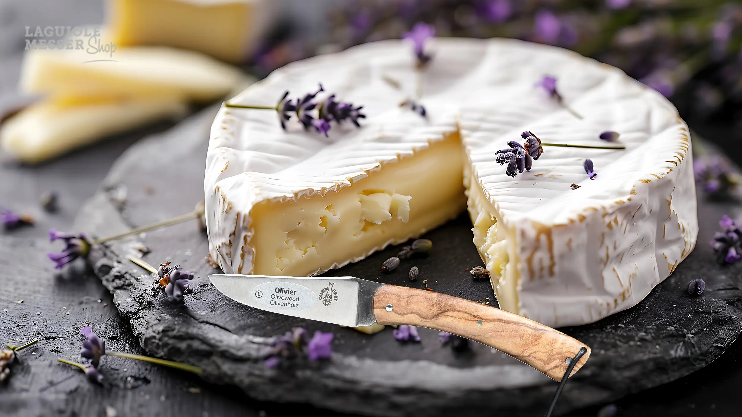 CAMEMBERT Messer von Laguiole en Aubrac mit Olivenholzgriff vor angeschnittenem Camembert auf Schieferplatte