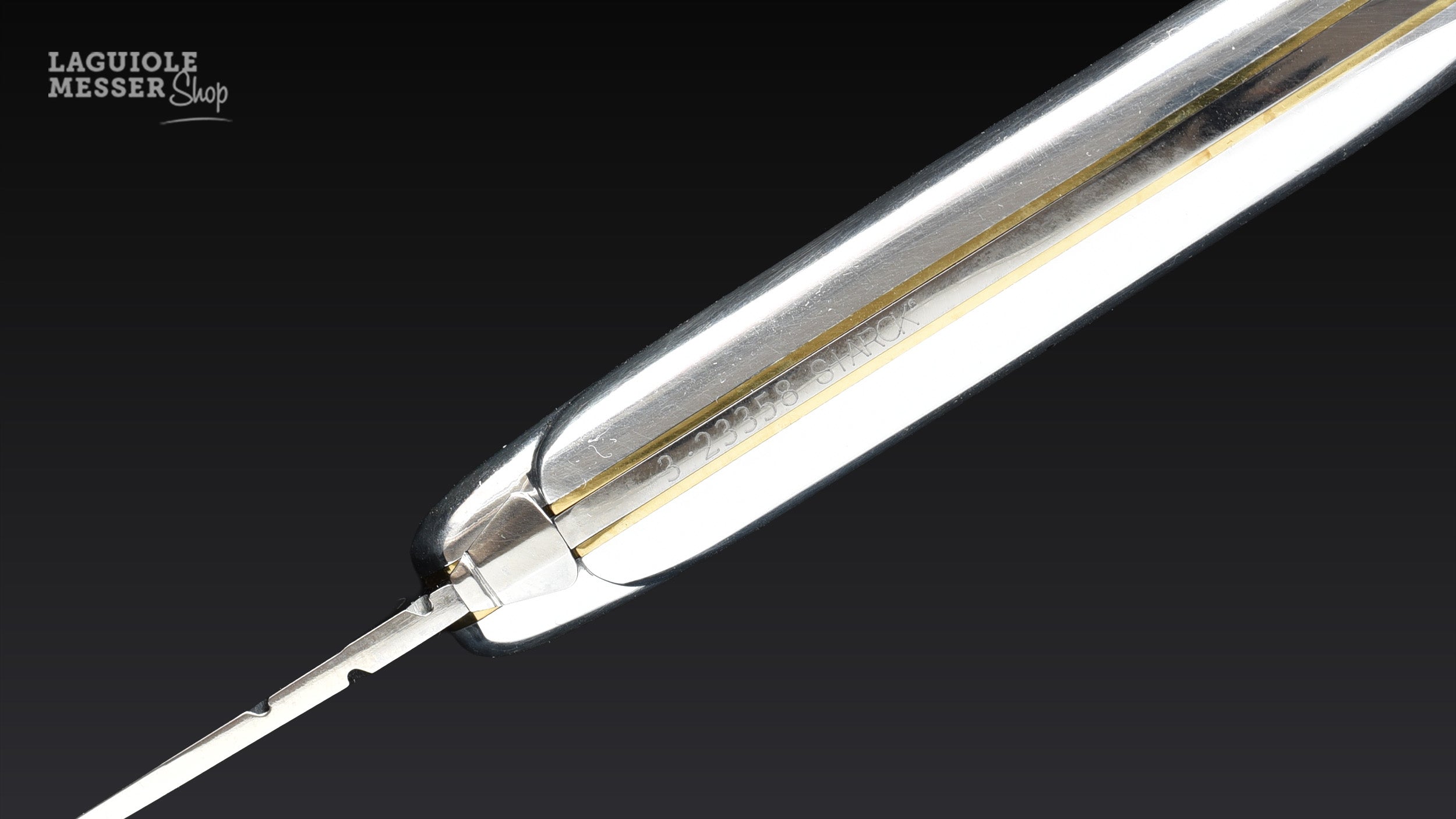 Detailansicht des Forge de Laguiole Philippe Starck Taschenmessers mit Aluminiumgriff, feinem Messingstreifen und Gravur am Messerrücken