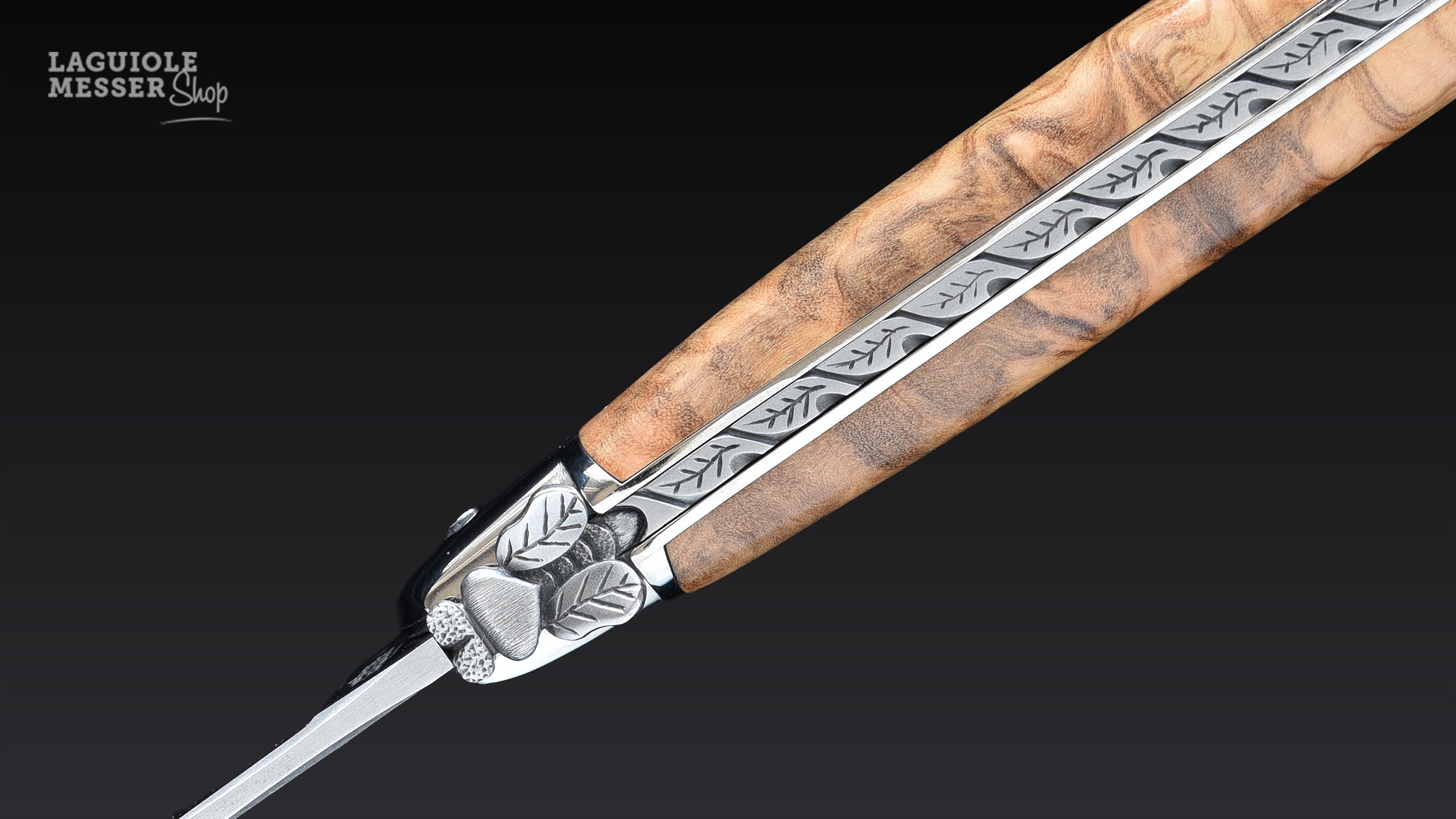 Detail des Laguiole Taschenmessers von Virgilio Muñoz mit Olivenholz, geschmiedeter Mouche und fein verzierter Rückenarbeit